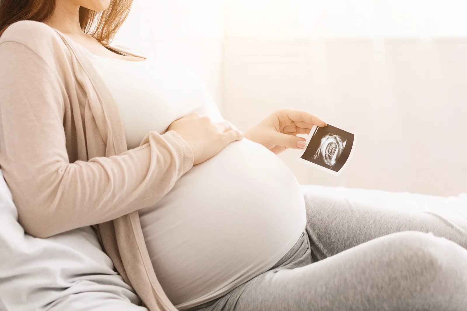 pregnant-woman-holding-ultrasound-photo-at-home